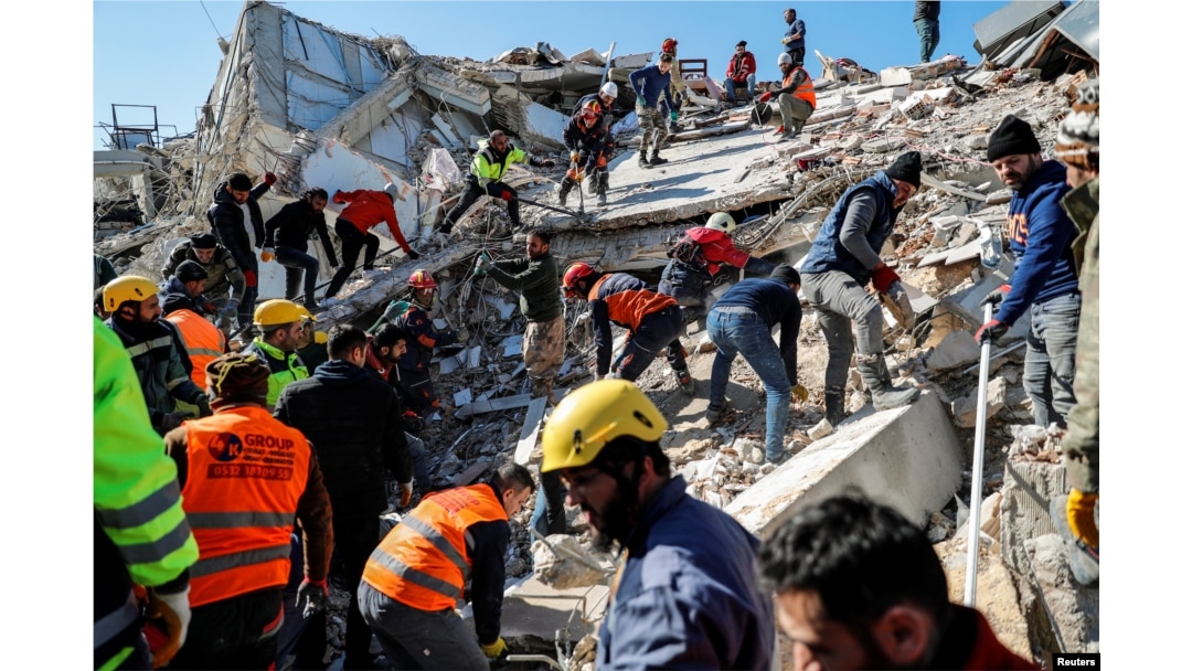 Localnici și echipe de salvatori lucrează la locul unei clădiri prăbușite de cutremur, în Hatay, Turcia, 9 februarie 2023.