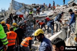 Localnici și echipe de salvatori lucrează la locul unei clădiri prăbușite de cutremur, în Hatay, Turcia, 9 februarie 2023.
