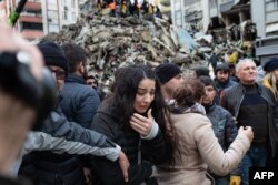 O femeie plânge în timp ce salvatorii caută supraviețuitori printre dărâmăturile clădirilor prăbușite din Adana, pe 6 februarie 2023.