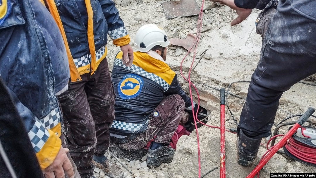 Salvatori sirieni caută persoane prinse sub dărâmăturile unei clădiri distruse din Afrin, Siria. 