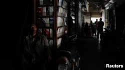 A man sits outside his shop during a nationwide power outage in Karachi on January 23.