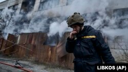 Украински пожарникар пред горяща сграда след руски обстрел на индустриална зона на град Херсон, 5 февруари 2023 г. 