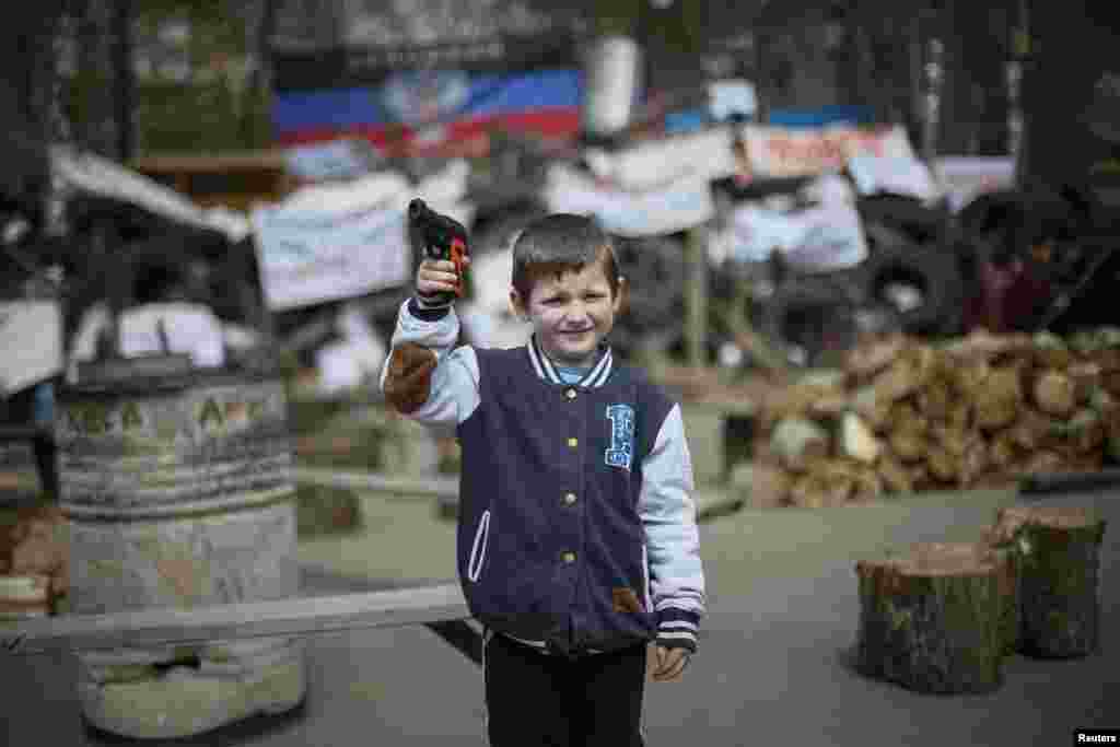 A boy with a toy gun poses for picture in front of barricades at police headquarters in the eastern Ukrainian town of Slovyansk. (Reuters/Gleb Garanich)