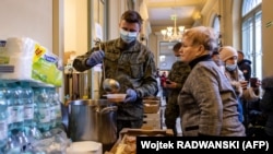 Војник дава храна на бегалци од Украина