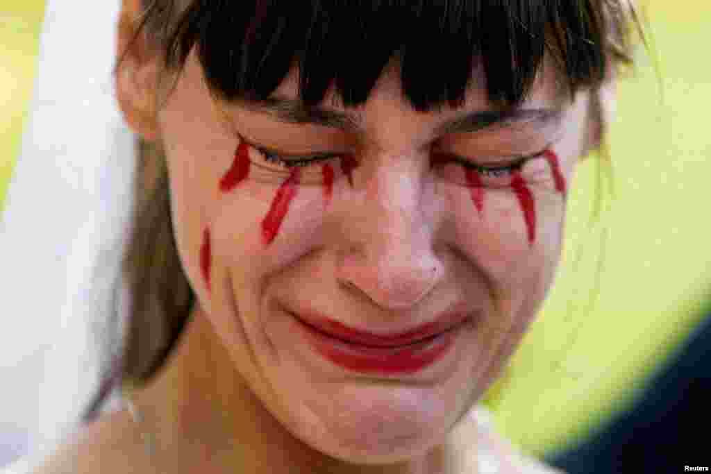 Жена с изкуствена кръв по лицето си. Сцената се развива пред посолството на Русия в Мексико сити в събота, 26 февруари.