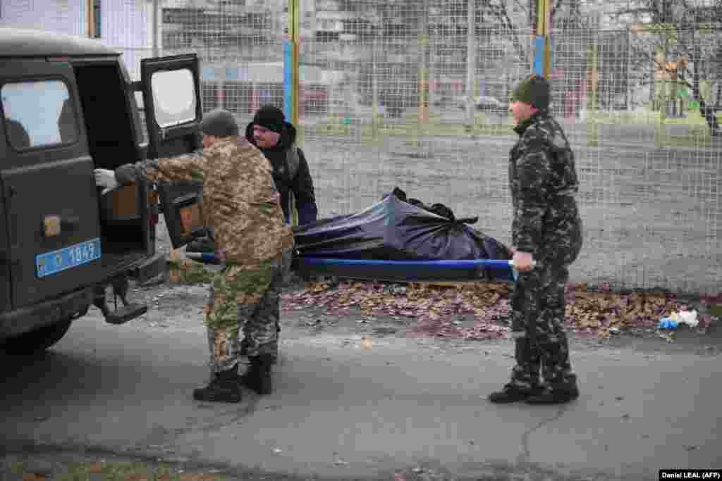 Ukrán katonák szállítják el egy férfinak a holttestét, akit lelőttek Kijev északi részén egy orosz páncélozott járműből 2022. február 25-én