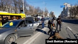 Ofițeri de poliție îi percheziționează pe ocupanții un automobil suspect oprit în trafic, în timp ce invazia ruusască a Ucrainei intrat în a cincea zi, Kiev, 28 februarie 2022. 