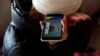 A woman from Ukraine listens to a speech by Ukrainian President Volodymyr Zelenskiy on a phone at a refugee shelter in Hungary on February 28. 