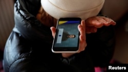 A woman from Ukraine listens to a speech by Ukrainian President Volodymyr Zelenskiy on a phone at a refugee shelter in Hungary on February 28. 