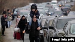 Ukrainian refugees walk alongside vehicles lining-up to cross the border from Ukraine into Moldova on February 26.