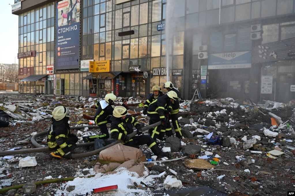 Zjarrfikësit shuan zjarrin në një bllok apartamentesh shumëkatëshe, që u godit nga bombardimet e fundit në Kiev më 26 shkurt 2022.