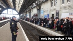 Люди чекають на потяг до Польщі на залізничному вокзалі Львова, Україна, 26 лютого 2022 року