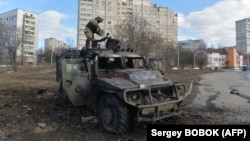 A soldier examines a destroyed Russian infantry mobility vehicle after a fight in Kharkiv on February 27.