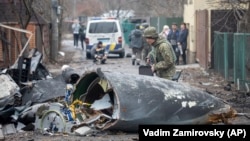 Украински войник разглежда останките от самолет, свален в Киев, 25 февруари 2022 г.