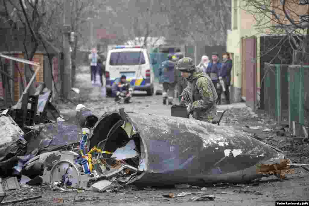 A Ukrainian soldier inspects fragments of a downed aircraft in Kyiv on February 25.