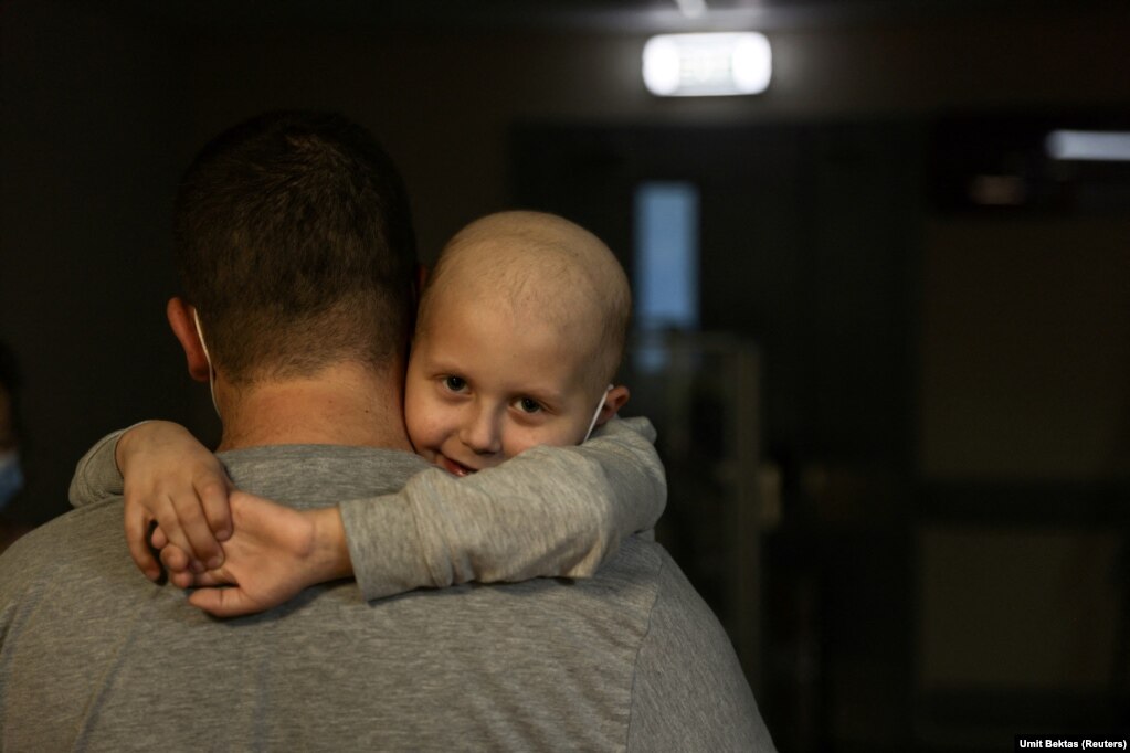Дитина, яка лікується від лейкемії, обіймає батька, під час прогулянки коридорами в підвалі дитячої лікарні «Охматдит» у Києві. Україна