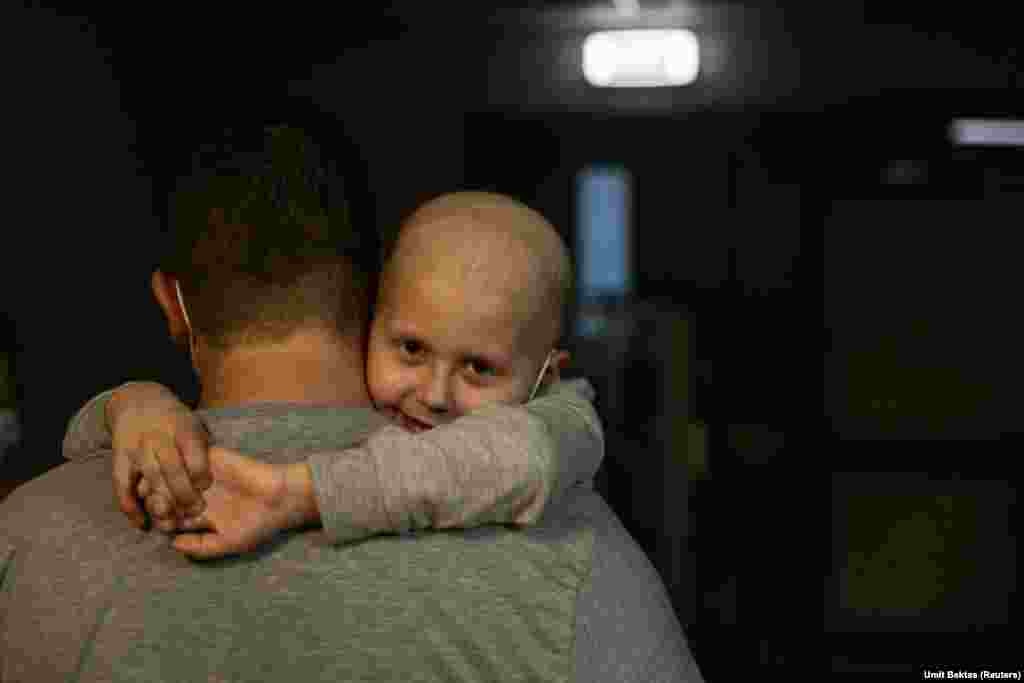 A child being treated for leukemia hugs his father as they walk along the hallways in the basement of Okhmadet Children&#39;s Hospital in Kyiv.