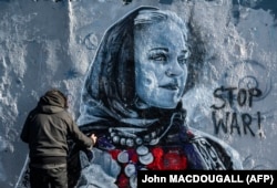 Berlin-based Colombian street artist Arte Vilu works on an anti-war mural featuring a Ukrainian woman in traditional dress in Berlin on February 28.