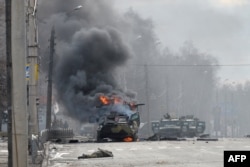 A Russian armored personnel carrier burns next to a soldier's body after fighting in Kharkiv on February 27, 2022.