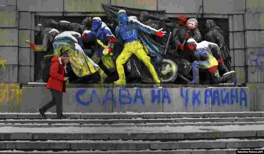 A man in the Bulgarian capital, Sofia, walks by a monument to the Soviet Army that has been spray-painted in the colors of the Ukrainian flag with the words &quot;Glory to Ukraine.&quot;