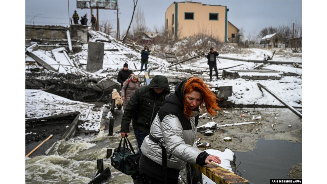 Un grup de civili traversează un pod distrus de bombardamente în Kiev, 1 martie 2022.