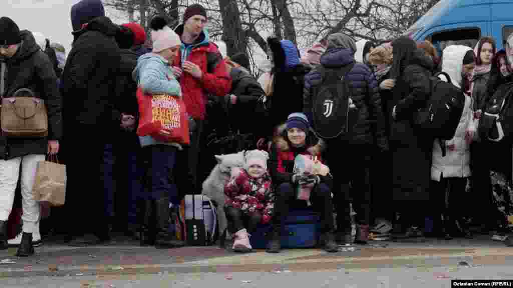 Deși așteaptă de trei zile în Ucraina pentru a trece frontiera în România, doi copii zâmbesc de pe valiza în care familia lor are toate lucrurile. Vama Siret, în Ucraina, 27 februarie 2022.