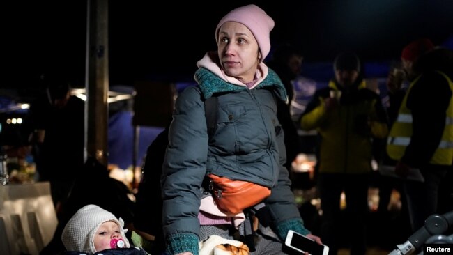 Një nënë qëndron me fëmijën e saj në një qendër të ndihmës pasi iku nga pushtimi rus i Ukrainës. Fotograifa është shkrepur në Prezmysl, Poloni më 27 shkurt, 2022. Reuters/Bryan Woolston