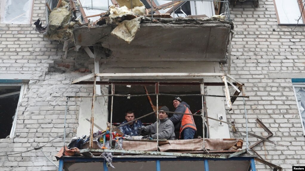 Луѓе на балкон од оштетена зграда во градот Јасиноватја, 2 март 2022