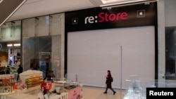 A woman walks past a closed re:Store, an Apple reseller shop, at a mall in St. Petersburg, Russia. 