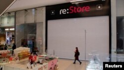 Një grua kalon pranë një dyqani të mbyllur të 're:Store', që është një dyqan në Shën Petersburg që shiste produkte të kompanisë Apple. Kompania Apple ka pezulluar shitjet e të gjitha produkteve në Rusi.