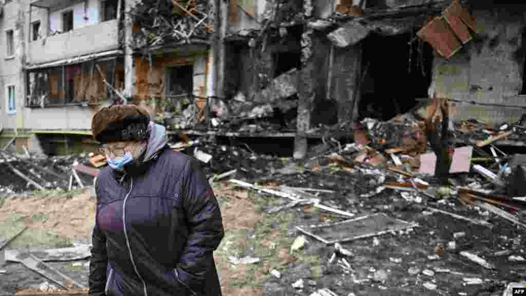 Жена поминува покрај оштетените згради при нападите на Киев, 25 февруари 2022