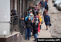 People stand in line to withdraw U.S. dollars and euros from an ATM in St. Petersburg, Russia, on February 25.