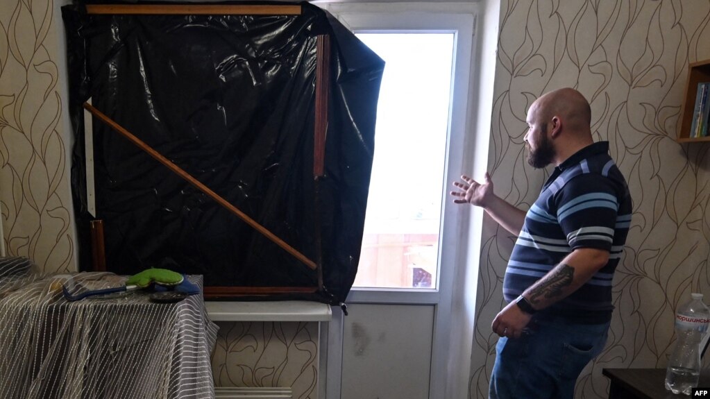 Маж гледа низ прозорецот од неговиот стан во Киев, оштетен при нападите врз украинскиот главен град, 28 февруари 2022