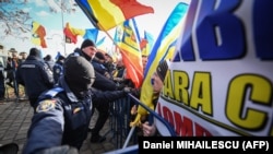 Romanian police push back protesters trying to enter the secured perimeter of the Romanian parliament headquarters during a demonstration in Bucharest on December 21.