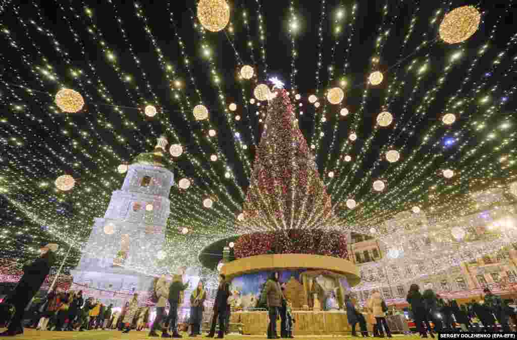 Kyiv residents walk around the Ukrainian capital&#39;s main Christmas tree in front of St. Sophia&#39;s Cathedral. The tree is 31 meters high and features more than 10,000 decorations