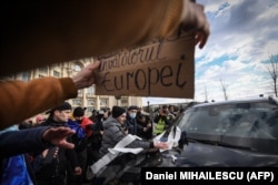 Protestatarii chemați de AUR aruncă hârtie igienică și scuipă pe parbrizul unei mașini aparținând unei misiuni diplomatice în timp ce asaltează intrarea Parlamentului României în timpul unui protest în fața sediului Parlamentului României din București, 21 decembrie 2021, dimineața