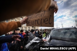 Protesters throw toilet paper and spit on the windshield of a car belonging to a diplomatic mission as they storm the parliament on December 21.