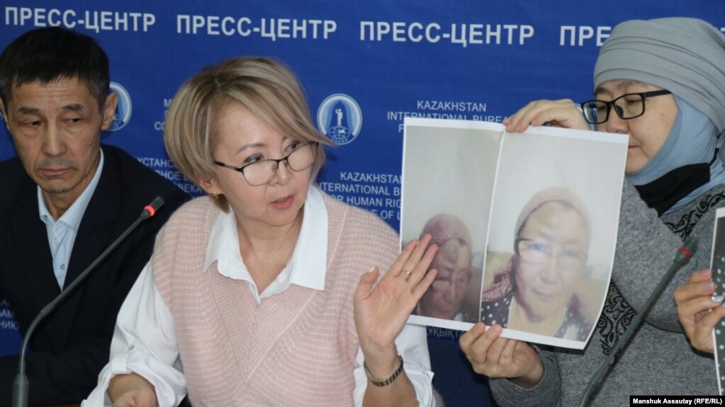 Алматинская активистка Карлыгаш Турманова показывает на пресс-конференции портрет пострадавшей от действий полиции Нинагуль Жуманиязовой. 22 декабря 2022 года 