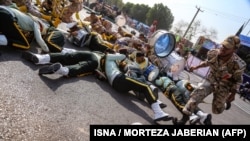 FILE: This picture was taken on September 22 in the southwestern Iranian city of Ahvaz shows a soldier running past injured comrades lying on the ground at the scene of an attack on a military parade.