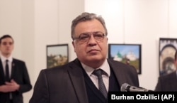 Russian Ambassador to Turkey Andrei Karlov speaks at a gallery in Ankara on December 19, just before the gunman (left) opened fire.