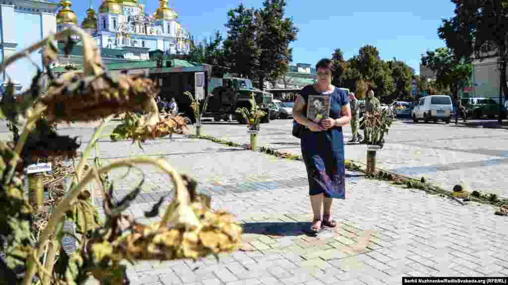Мама з портретом сина проходить по символічному «зеленому коридору» з назвами населених пунктів, через які виходили війська з Іловайська, де їх обстрілювали російські війська