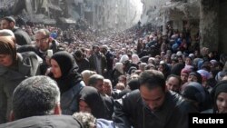 Residents wait to receive food aid distributed by the UN at the Yarmouk camp, south of Damascus, on January 31, 2014.