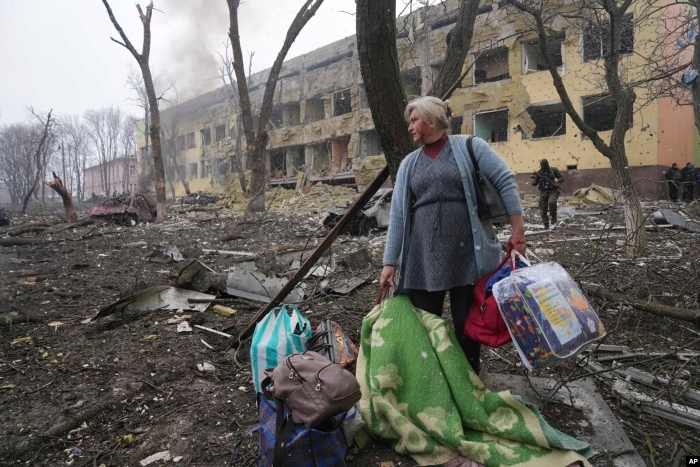 Një grua, e përgjakur, shihet duke ecur pranë ndërtesës së shkatërruar të spitalit të fëmijëve, në Mariupol, më 9 mars.