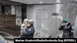 Український поліцейський несе дитину на руках під час евакуації із Ірпеня, зруйнованого внаслідок вторгнення Росії в Україну. 9 березня 2022 року