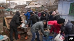 Oamenii fac coadă pentru a lua apă la o fântână de la marginea orașului Mariupol pe 9 martie.