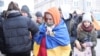 A Ukrainian woman wrapped in a Ukrainian flag arrives with other refugees in Poland in March 2022. The Kremlin has targeted Poland, in particular, with social media disinformation campaigns aimed to stir up public resentment toward refugees. 