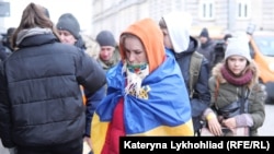 Українка, загорнута в український прапор, прибуває з іншими біженцями до Польщі в березні 2022 року