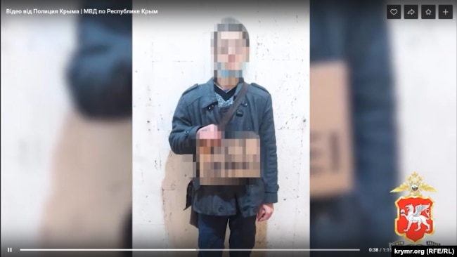 Крымчанин на одиночном пикете с антивоенным плакатом, содержание которого на видеоролике заретушировано российской полицией, март 2022 года