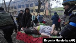 Sebesült kismamát szállítanak el a mentők és önkéntesek a mariupoli támadást követően 2022. március 9-én