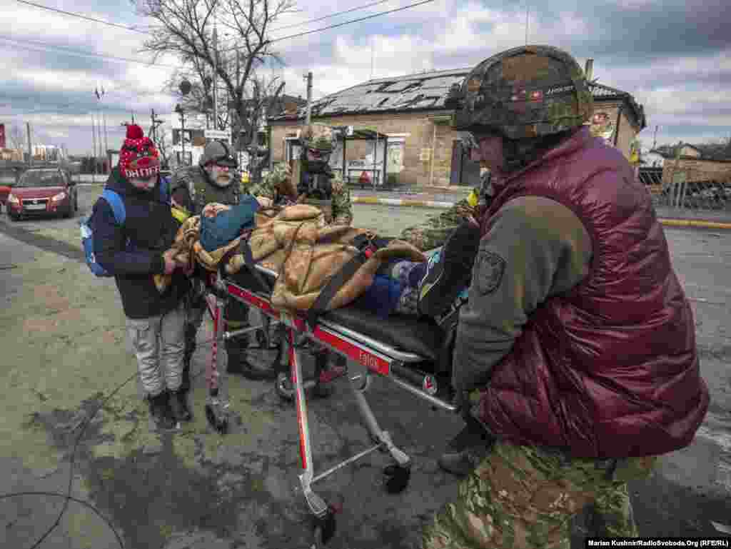 Ushtarakë ukrainas dhe civilë duke bartur me barelë një të sëmurë.&nbsp;